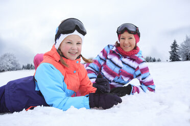 Deutschland, Masserberg, Mutter und Tochter liegen im Schnee und lächeln glücklich - VTF000095