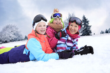 Deutschland, Masserberg, Mutter und Töchter liegen im Schnee und lächeln glücklich - VTF000096
