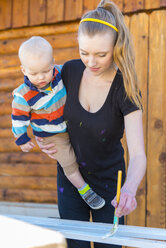 Junge Frau mit Kleinkind malt Gitterstäbe - ABAF001261