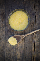 Bowl of corn semolina and wooden spoon on wooden table - LVF000720