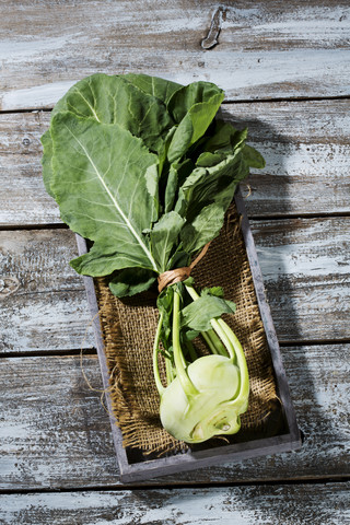 Kohlrabi (Brassica oleracea) auf Jute, Holzteller und Tisch, lizenzfreies Stockfoto