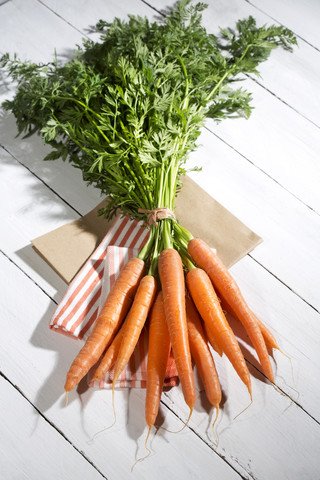 Bunch of organic carrots on cloth and white wooden table stock photo