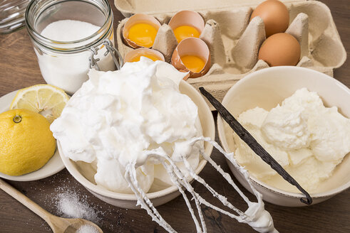 Bowl of beaten egg white and other baking ingredients of meringues on wooden table - CSTF000028