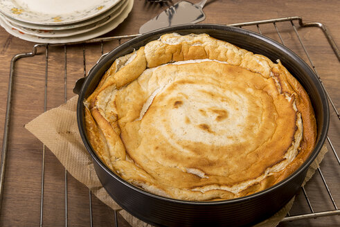 Baked cheese cake cooling down in cake pan on wooden table - CSTF000059