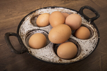Frische braune Eier in alter Pfanne auf Holztisch - CSTF000060