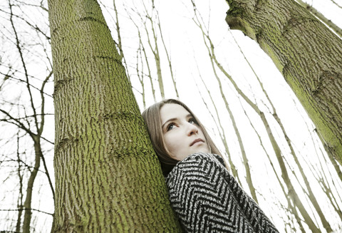 Porträt eines jungen Mädchens, das sich an einen Baumstamm lehnt, lizenzfreies Stockfoto