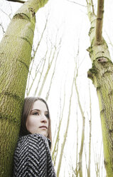 Portrait of teenage girl leaning against tree trunk - JATF000674