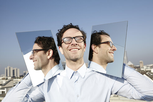 Portrait of smiling man holding two mirrors - FMK000983