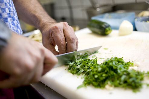 Germany, Munich, italian restaurant, Chef slicing spices, herbs and garlic - LB000579