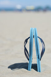 Pair of light blue flip-flops standing in the sand - ASF005267