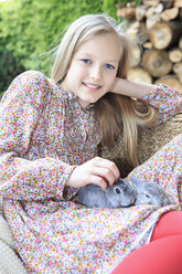 Porträt eines lächelnden Mädchens mit zwei Kaninchen auf dem Schoß - VTF000119