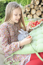 Lächelndes Mädchen füttert Kaninchen mit Erdbeeren - VTF000116