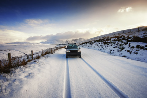 UK, Schottland, Isle of Skye, Cuillin Mountains, Allradfahrzeug auf verschneiter Straße, lizenzfreies Stockfoto