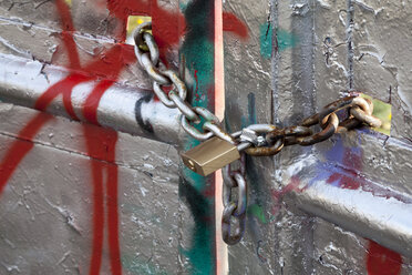 Germany, North Rhine-Westphalia, Muenster, chains with padlock on sprayed gate - WIF000425