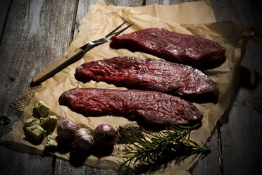 Beefsteak, garlic, rosemary, herb butter and pepper on baking paper - MAEF007984