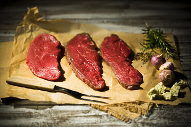 Beefsteak, Knoblauch, Rosmarin, Kräuterbutter und Pfeffer auf Backpapier - MAEF007983