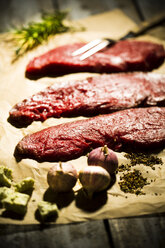 Beefsteak, Knoblauch, Rosmarin, Kräuterbutter und Pfeffer auf Backpapier - MAEF007982