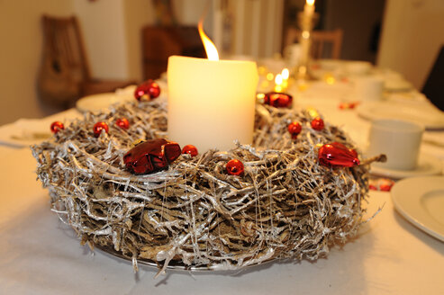 Advent wreath with lighted candle on laid table - LB000592