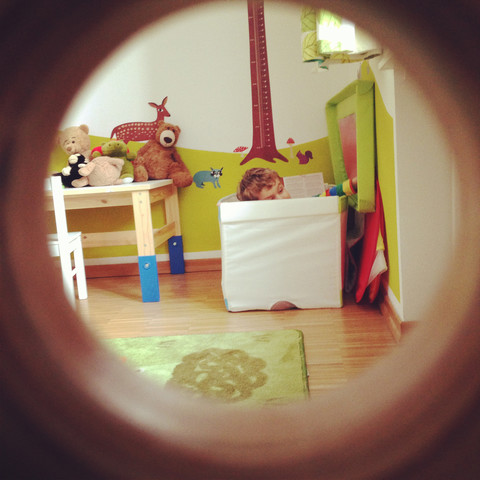 View through peephole into child's room with playing toddler stock photo