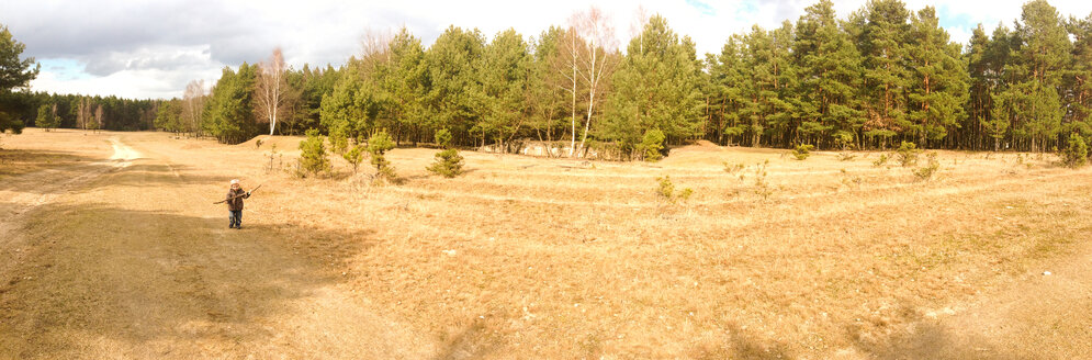 Deutschland, Brandenburg, Saarmund, Kind läuft auf einem Feld, Wald im Hintergrund - AFF000025