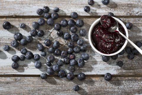 Schale mit Blaubeer- und Himbeermarmelade, Löffel und Blaubeeren auf Holztisch, Blick von oben, lizenzfreies Stockfoto