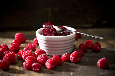 Schale mit Himbeermarmelade, Löffel und Himbeeren auf Holztisch - MAEF008005