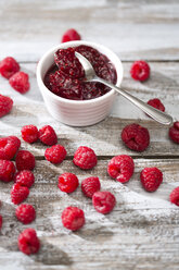 Schale mit Himbeermarmelade, Löffel und Himbeeren auf Holztisch - MAEF008002