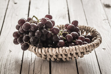 Basket of blue grapes on wooden table - SARF000273