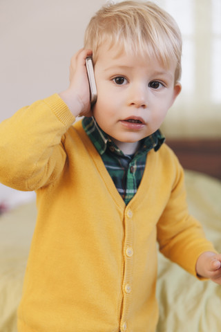 Porträt eines Kleinkindes, das mit einem Smartphone telefoniert, lizenzfreies Stockfoto