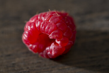 Single raspberry on dark wood - MAEF007995