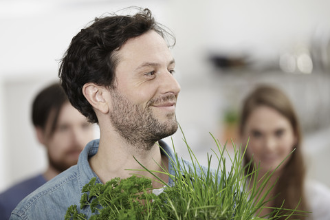 Lächelnder Mann mit Kräutern in der Küche, lizenzfreies Stockfoto