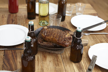 Steak in der Bratpfanne und Bierflaschen auf dem Holztisch - FMKF001012