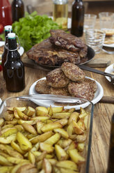 Teller mit Kartoffeln, Steaks und Fleischbällchen auf Holztisch - FMKF001071