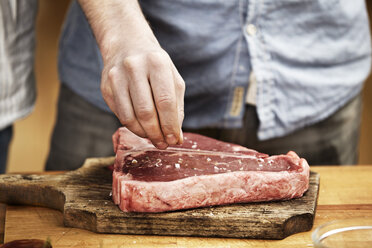 Mann bereitet Steak in der Küche zu - FMKF001084