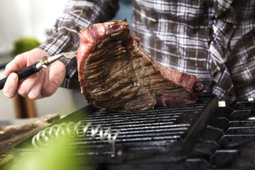 Nahaufnahme einer Frau, die in der Küche ein Steak grillt - FMKF001056