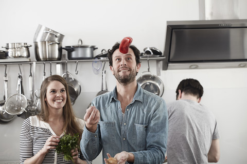 Mann jongliert mit Lebensmitteln in der Küche, lizenzfreies Stockfoto
