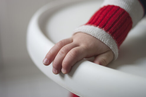 Hand eines Kleinkindes, das den Rand eines Kinderstuhls festhält - MUF001440