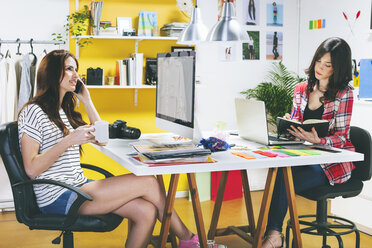 Zwei Modebloggerinnen sitzen am Schreibtisch im Büro - EBSF000055