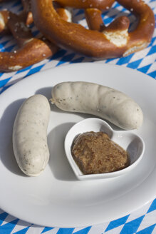 Weißwurst und süßer Senf in einer herzförmigen Schale auf einem Teller, Brezeln - YFF000064