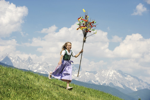 Austria, Salzburg State, Altenmarkt-Zauchensee, girl with Palmbusch running down alpine meadow stock photo