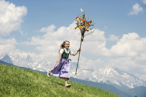 Österreich, Bundesland Salzburg, Altenmarkt-Zauchensee, Mädchen mit Palmbusch läuft über Almwiese, lizenzfreies Stockfoto