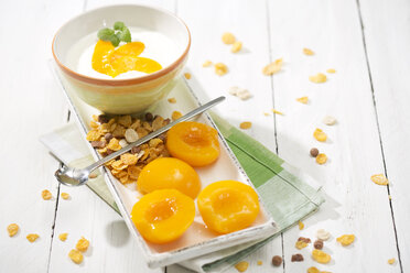 Bowl of lactose-free yogurt with pieces of peach on white wooden table - MAEF008085
