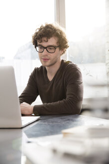 Porträt eines jungen Architekten mit Laptop in seinem Büro - FKF000426