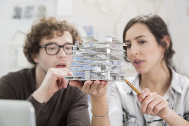 Porträt von zwei jungen Architekten, die ein Architekturmodell im Büro betrachten - FKF000431