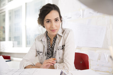 Portrait of young female architect at her desktop in office - FKF000444
