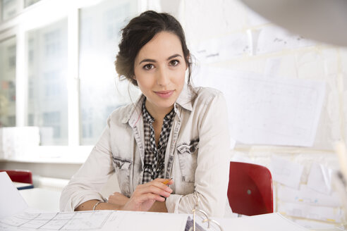 Porträt einer jungen Architektin an ihrem Schreibtisch im Büro - FKF000444