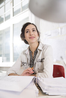 Porträt einer jungen Architektin an ihrem Schreibtisch im Büro - FKF000445