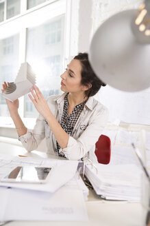 Porträt einer jungen Architektin mit Architekturmodell an ihrem Schreibtisch im Büro - FKF000447