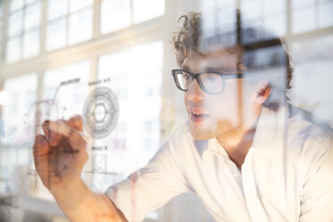 Portrait of young architect marking construction plan in office - FKF000455