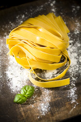 Fresh Pappardelle classico, basil and flour on wooden table - MAEF008105